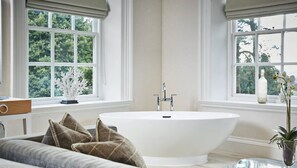 Une salle de bain avec une baignoire sur pieds, un lavabo et une fenêtre donnant sur un paysage verdoyant.