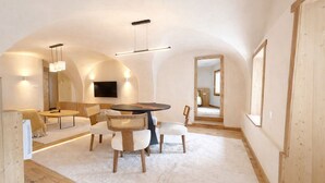 Un intérieur moderne avec une table de salle à manger ronde, des chaises rembourrées, un téléviseur à écran plat et un grand miroir.