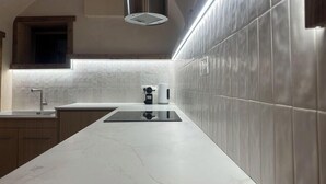 Une cuisine moderne dotée d’un plan de travail blanc, d’un dosseret en acier inoxydable et d’un four encastré.