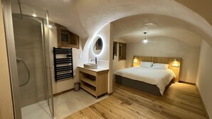 Une chambre dotée d’un grand lit, d’une coiffeuse intégrée, d’une douche et d’un plafond cintré.