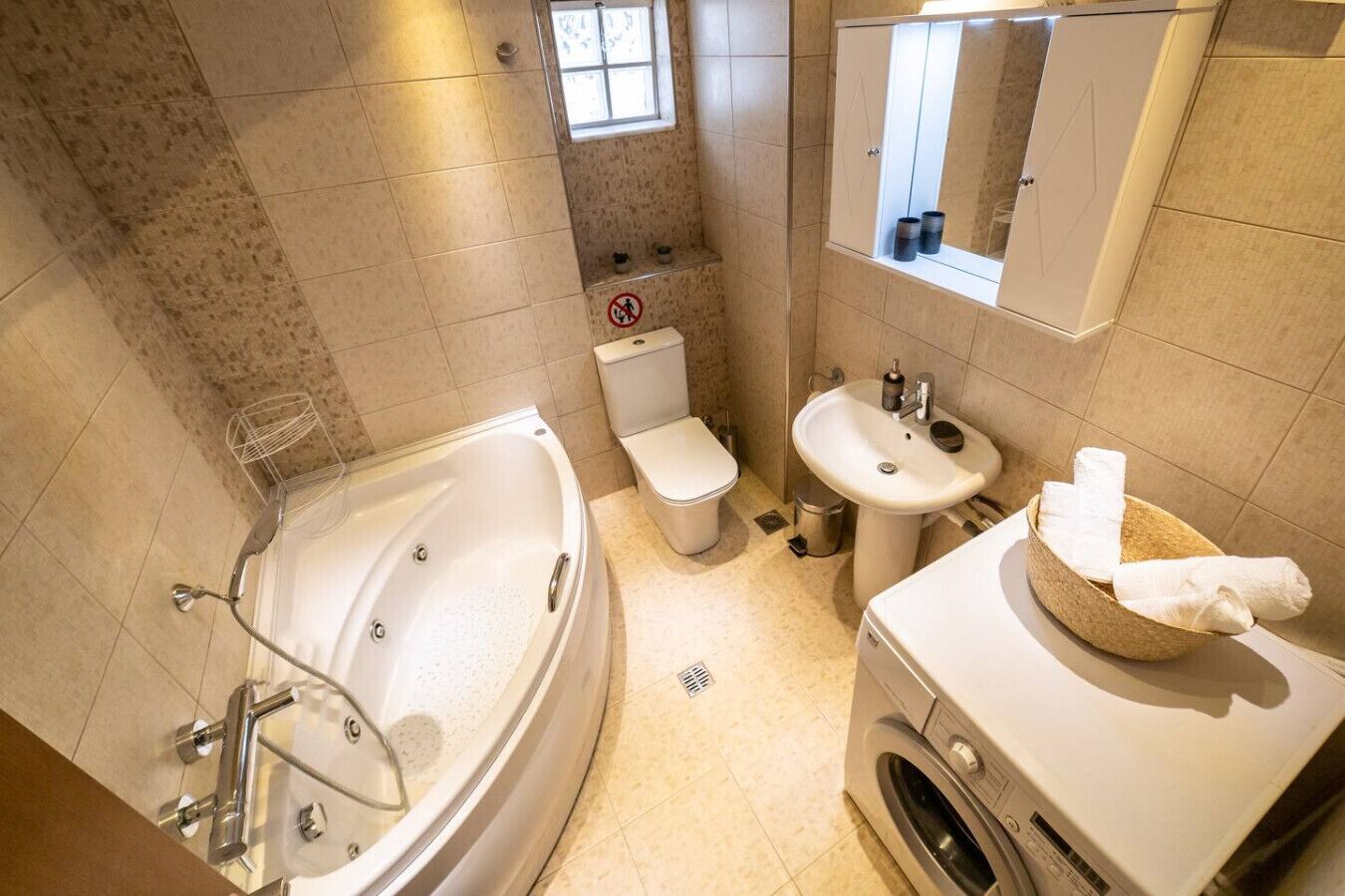Une salle de bain équipée d’une baignoire, de toilettes, d’un lavabo et d’un lave-linge.
