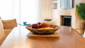 Una mesa de madera con una cesta tejida que contiene manzanas y plátanos.