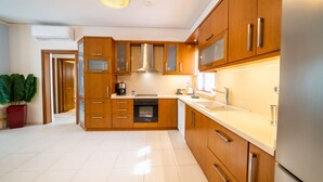 Una cocina moderna con armarios de madera, electrodomésticos de acero inoxidable y un amplio ventanal que proporciona luz natural.