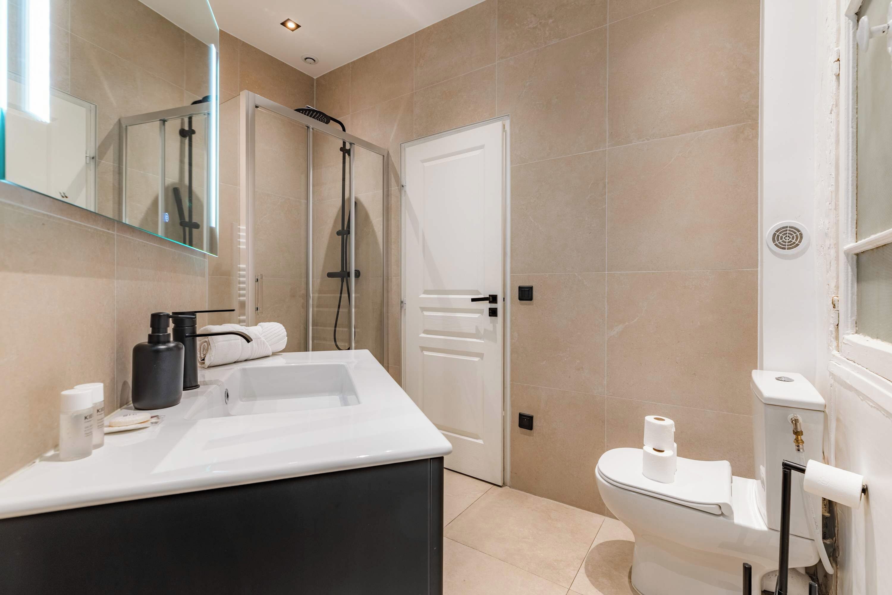 A modern bathroom with a glass shower enclosure, a white toilet, and a vanity with a mirror.