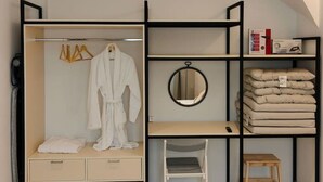 Ein gemütliches Schlafzimmer mit Einbauschrank, Nachttisch, rundem Spiegel und kleinem Holzschemel.