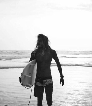 Iemand loopt langs het strand met een surfplank.