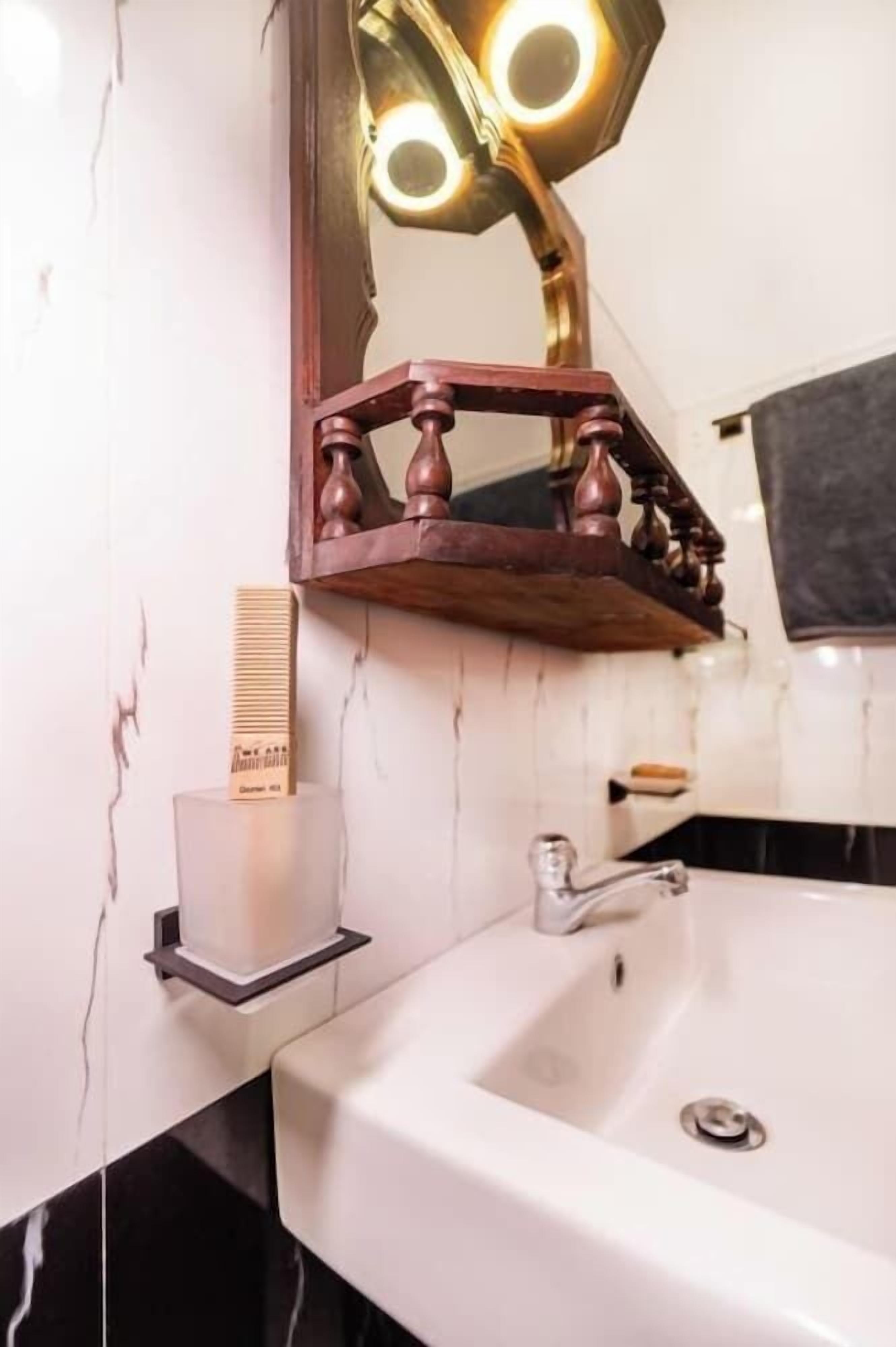 A bathroom with a white sink, a mirror with a wooden frame, and a towel hanging on the wall.