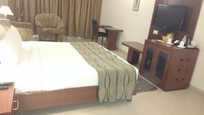 A hotel room with a bed, a desk, a chair, a television, and a cabinet. - Lemon Tree Hotel Baddi (Baddi)