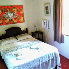 Ein Schlafzimmer mit einem Bett, einem Nachttisch, einer Wanduhr und einem Gemälde.