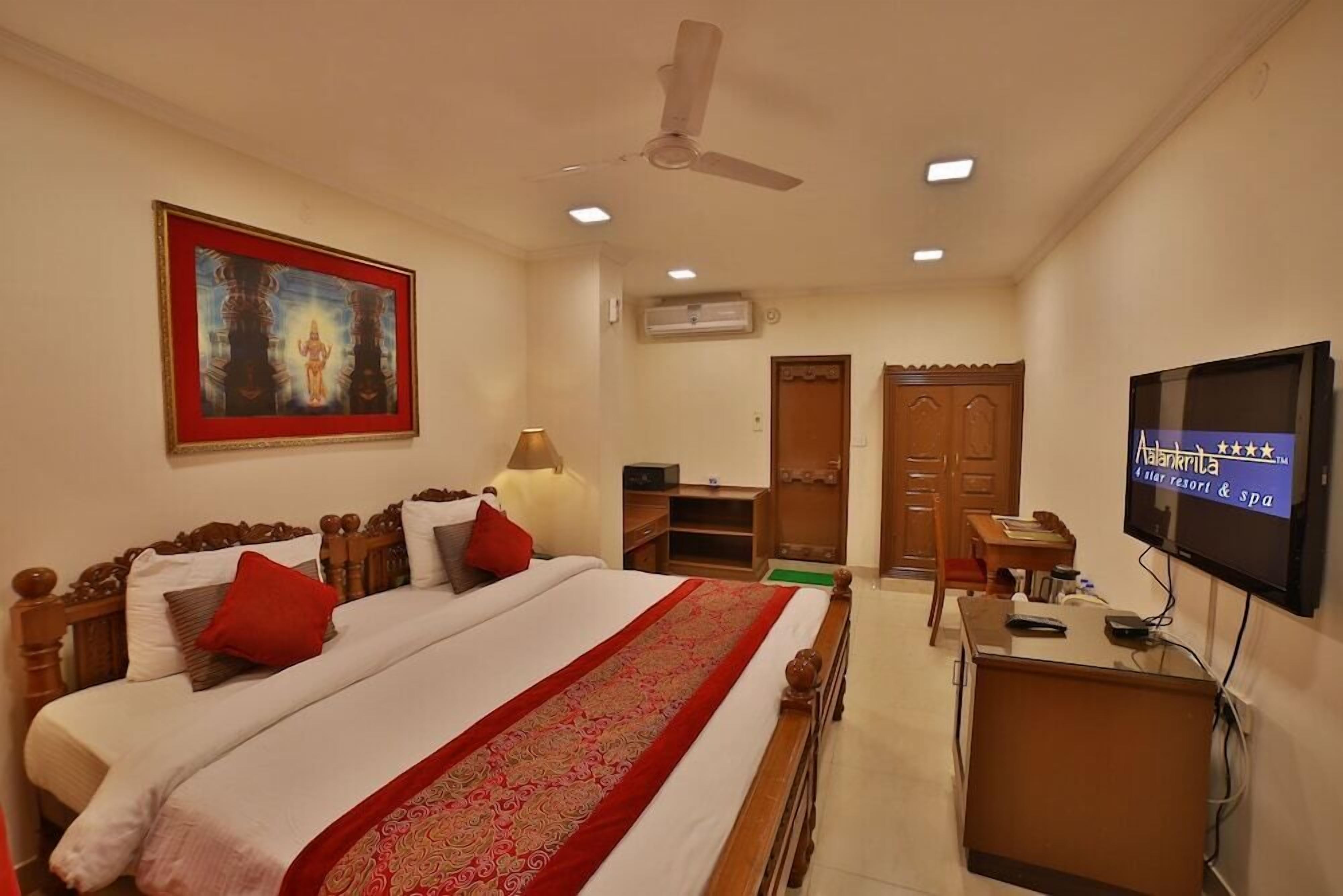 A hotel room with a bed, a desk, a TV, and a ceiling fan.