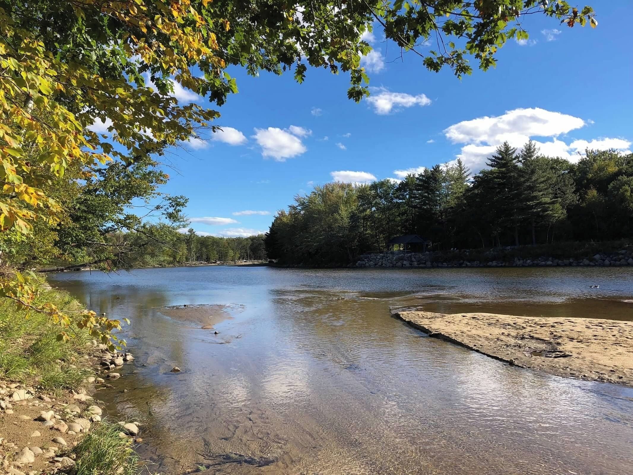 A river with clear water, surrounded by trees and a stone structure.