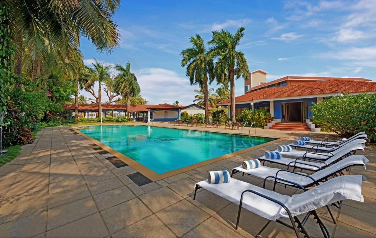 A swimming pool with lounge chairs and palm trees.