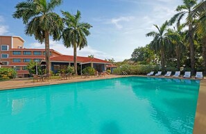 A swimming pool with lounge chairs and palm trees. - The Fern Kesarval Hotel & Spa Verna Plateau, Goa (Verna)