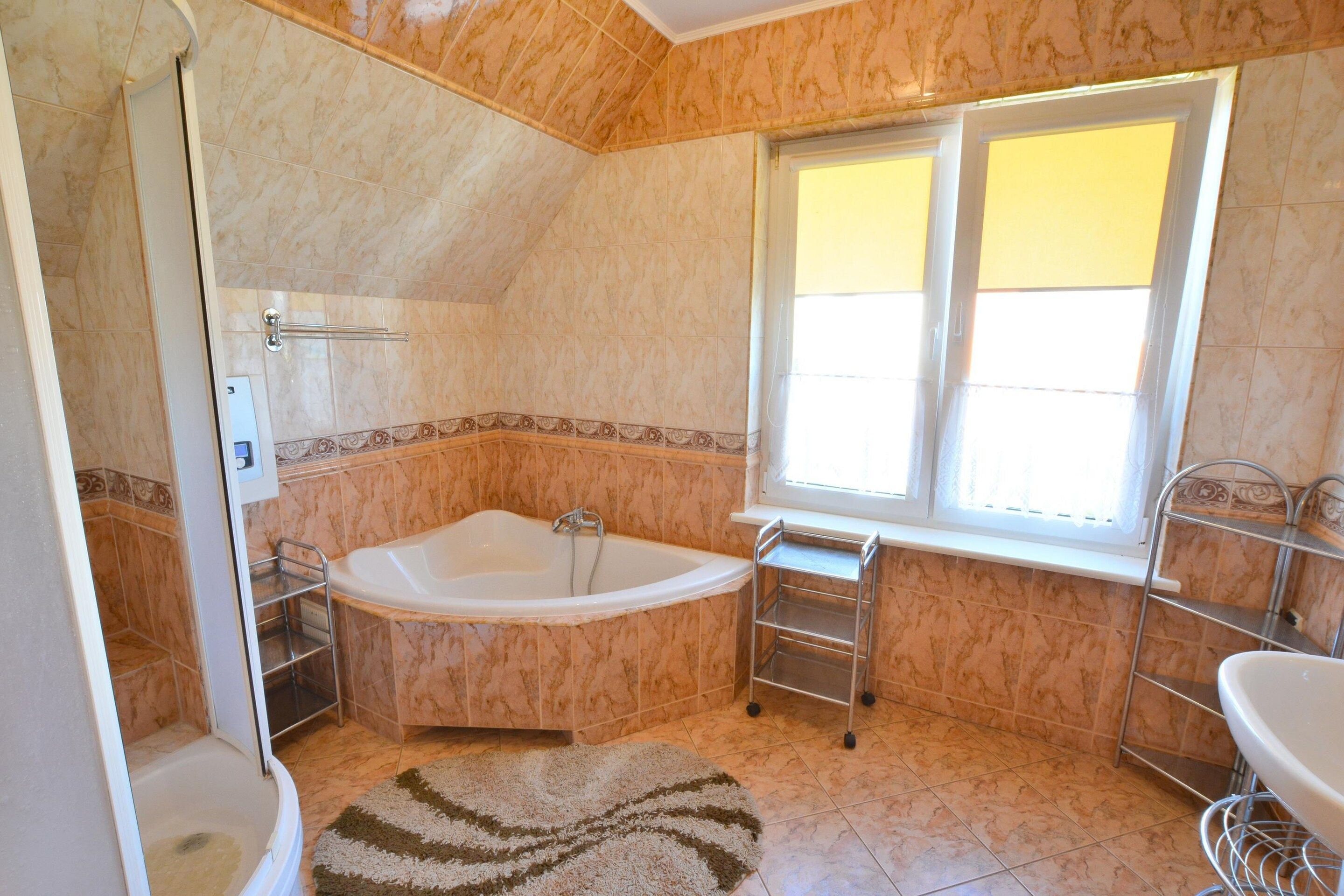 Ein Badezimmer mit Badewanne, Dusche, Fenster und Waschbecken.
