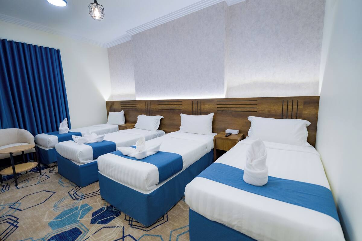 A hotel room with three beds, a desk, and a chair.