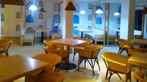 L’intérieur d’un restaurant est aménagé avec des tables et des chaises hautes, des luminaires suspendus et offre une vue sur le ciel grâce à de grandes fenêtres en arc de cercle.