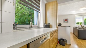 A modern kitchen with wooden cabinets, a dishwasher, and a window with a view of greenery. - Apartment 'Ferienwohnung' with Wi-Fi (Recklinghausen)