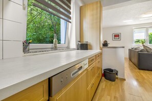 Una cocina moderna con armarios de madera, lavavajillas y ventana con vistas a zonas verdes.