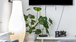 A white radiator, a potted plant, a TV on a wall, and a 'HOME' sign on a shelf. - Apartment 'Ferienwohnung' with Wi-Fi (Recklinghausen)