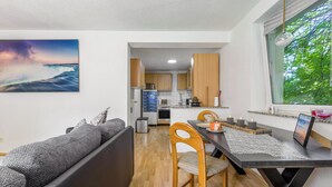 A modern kitchen with wooden cabinets, a dining area with a table and chairs, and a large window with a view of trees. - Apartment 'Ferienwohnung' with Wi-Fi (Recklinghausen)