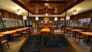 A restaurant with wooden furniture and a central table displaying a menu. - Rimba Orangutan Eco Lodge (Kumai)