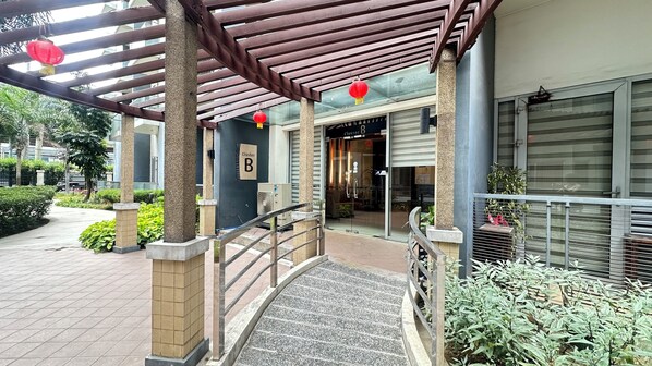 A hotel entrance with a covered walkway, a sign indicating 'Cluster B', and a gated entrance.