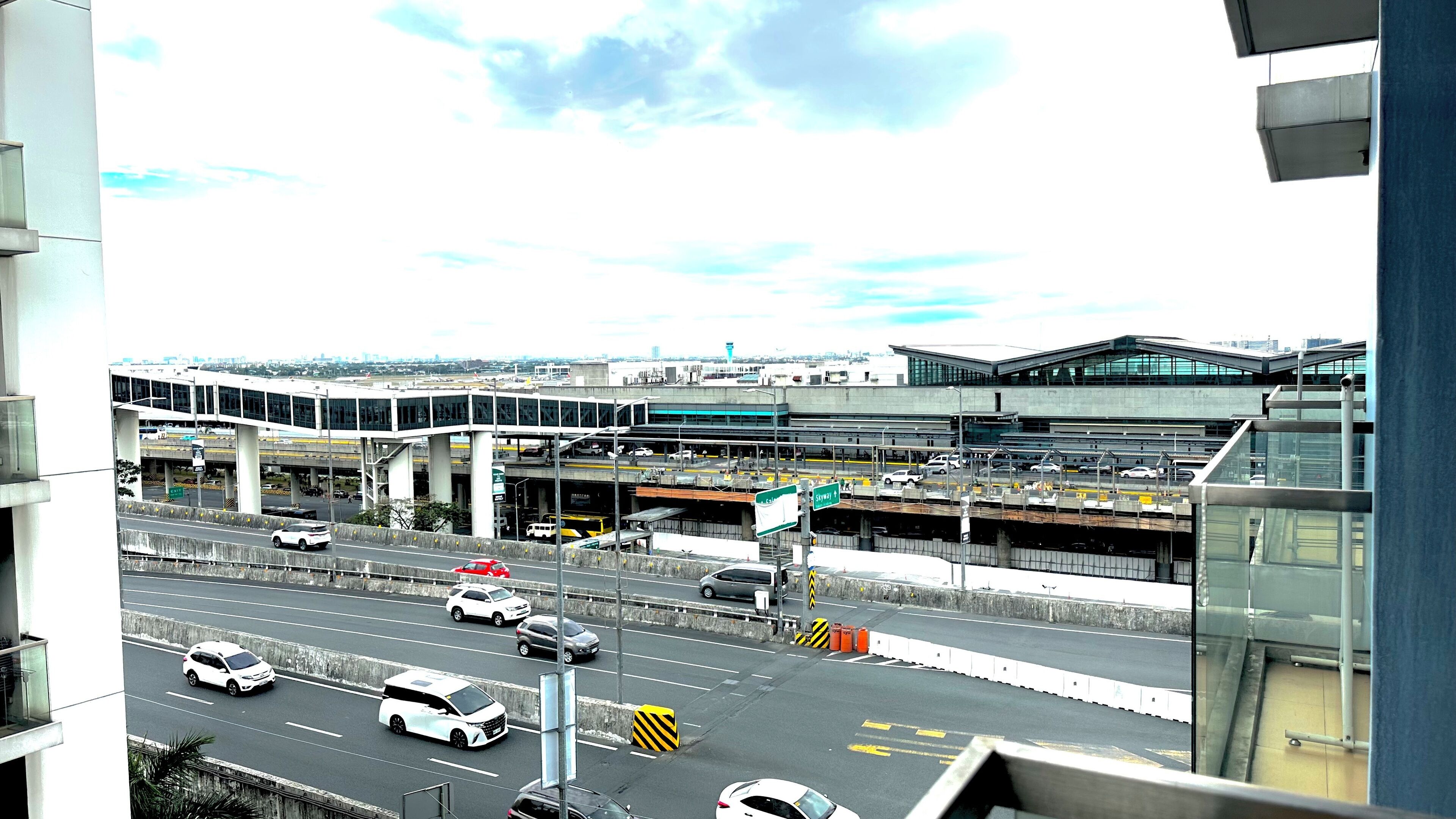 A multi-level highway interchange with vehicles, overpasses, and a modern building with large windows.
