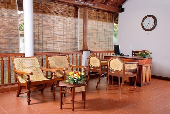 A room with wooden furniture, including chairs and a desk, and a clock on the wall. - Lemon Tree Vembanad Lake Resort Muhamma (Cherthala)