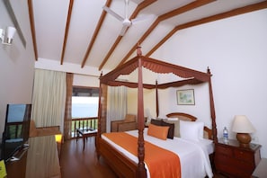 A four-poster bed with a balcony, a television, and a wooden nightstand with a lamp. - Lemon Tree Vembanad Lake Resort Muhamma (Cherthala)