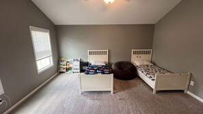 Ein Schlafzimmer mit zwei Betten, einem Bücherregal, einem Sitzsack und einem Fenster.
