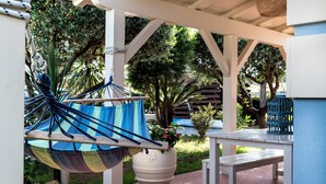 A hammock hanging under a white pergola, a white table, and a potted plant with pink flowers. - Jasmine Suite Bath Cavallone Directly on the beach, with TENT INCLUDED (Lido di Camaiore)