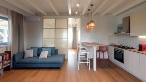 A modern living room with a sofa, a dining area with a table and chairs, and a kitchen with a stove and cabinets. - Jasmine Suite Bath Cavallone Directly on the beach, with TENT INCLUDED (Lido di Camaiore)