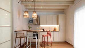 A modern kitchen with wooden flooring, white cabinets, and two pendant lights. - Jasmine Suite Bath Cavallone Directly on the beach, with TENT INCLUDED (Lido di Camaiore)