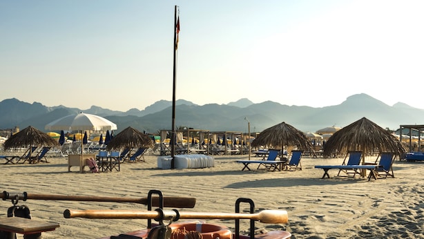 A beach with lounge chairs, a boat, and a flagpole. - Jasmine Suite Bath Cavallone Directly on the beach, with TENT INCLUDED (Lido di Camaiore)