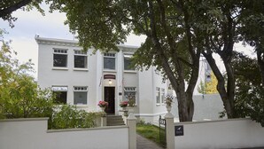 Een wit gebouw met een bord waarop 'HRAFNINN GUESTHOUSE' staat.