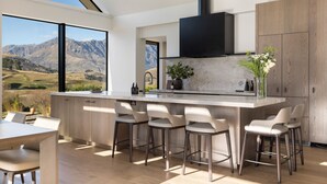 Une cuisine moderne dotée d’un grand îlot central, de tabourets de bar et offrant une vue sur les montagnes.