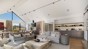Un vaste espace de vie agrémenté d’une grande fenêtre donnant sur un paysage pittoresque, une cuisine moderne équipée d’appareils électroménagers intégrés et un coin salon confortable avec des canapés et une table basse.