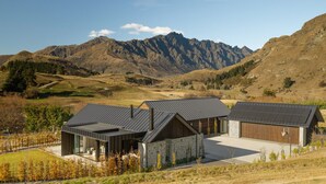 Une maison moderne avec une façade en pierre et un toit en métal, située dans un paysage montagneux.