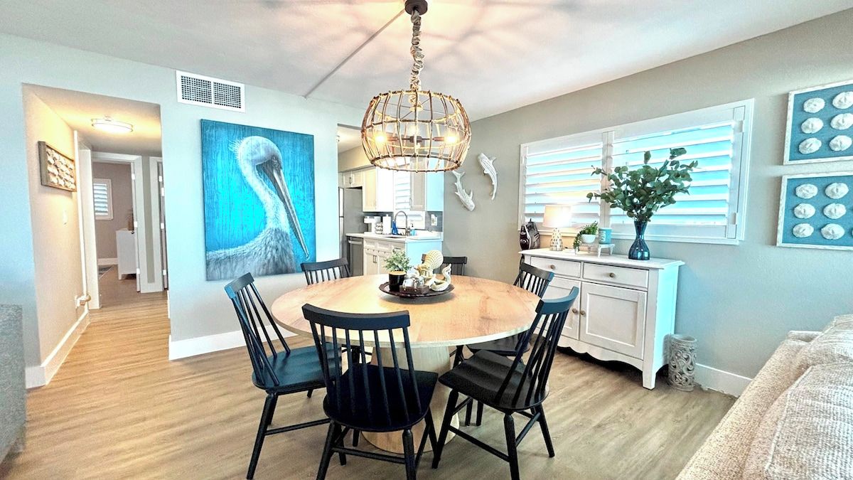 A dining area with a round table, black chairs, and a chandelier.