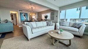Ein modernes Wohnzimmer mit einem hellgrauen Sofa, einem runden Couchtisch und einem Essbereich mit einem blauen Sofa.