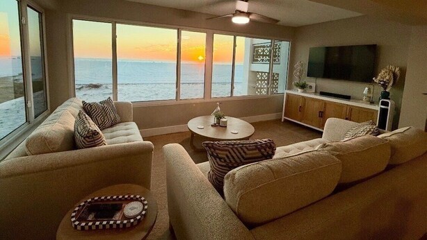Ein Wohnzimmer mit Sofa, Couchtisch und Fernseher mit Blick auf einen Sonnenuntergang.