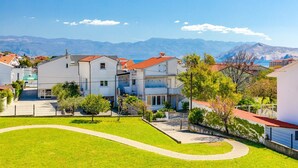 A residential area with houses, a paved driveway, and a view of mountains. - Newly decorated apartment in a quiet part of Baška (Baška)