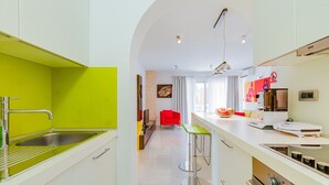 A modern kitchen with a bright green accent wall, stainless steel appliances, and a central island with stools. - Newly decorated apartment in a quiet part of Baška (Baška)