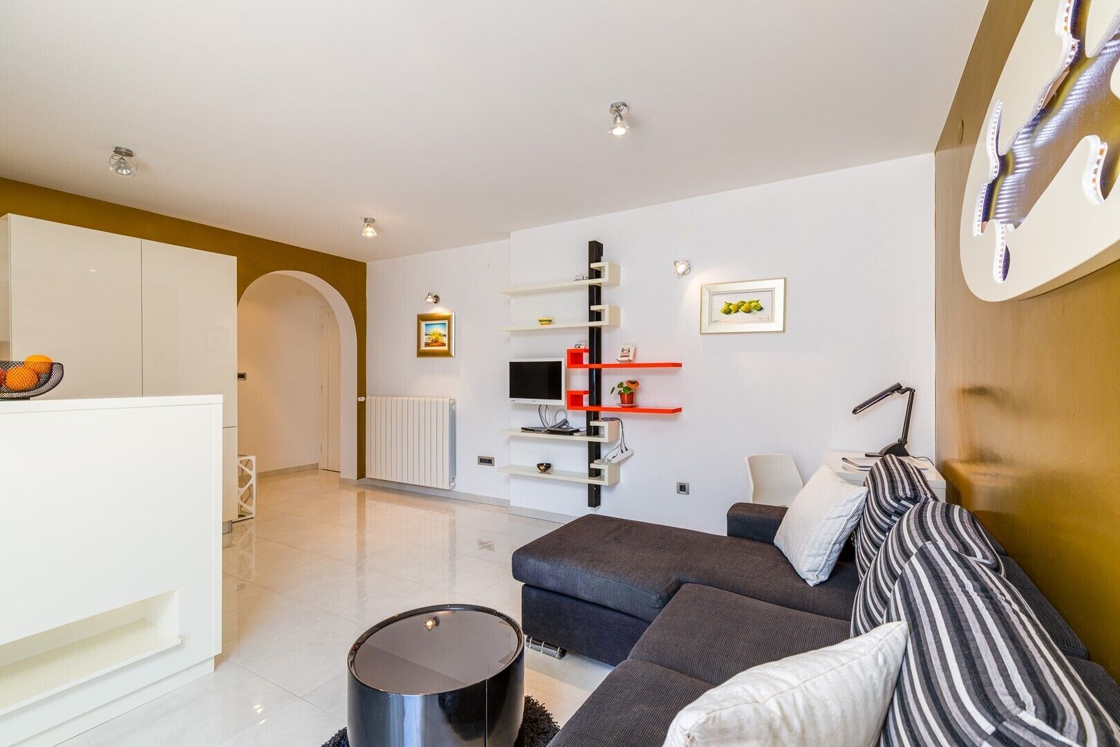 A modern living room with a sofa, a coffee table, and a TV mounted on a wall.