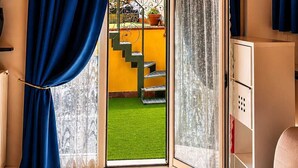 Habitación con techo de madera, puerta corredera de vidrio que da a un área exterior con pared amarilla y una escalera.