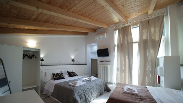 Un dormitorio con cama, mesita de noche y televisión.