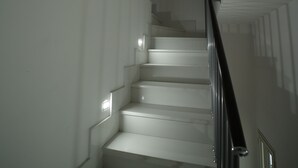 Una escalera con paredes blancas y barandilla de metal.