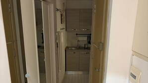 Un pasillo estrecho con una zona de cocina al final, que incluye armarios, un lavamanos y un radiador.