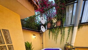 Un jardín trasero con césped artificial, un jacuzzi, plantas en macetas y una cerca de bambú.