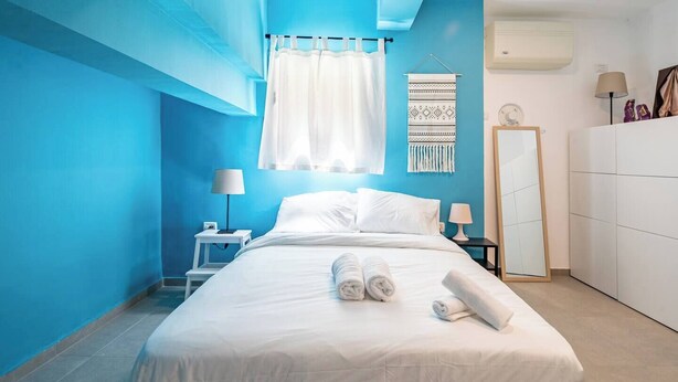 A bedroom with a bed, white bedding, a nightstand, a lamp, a mirror, and a wardrobe. - Port city haifa- beachfront complex (Haifa)